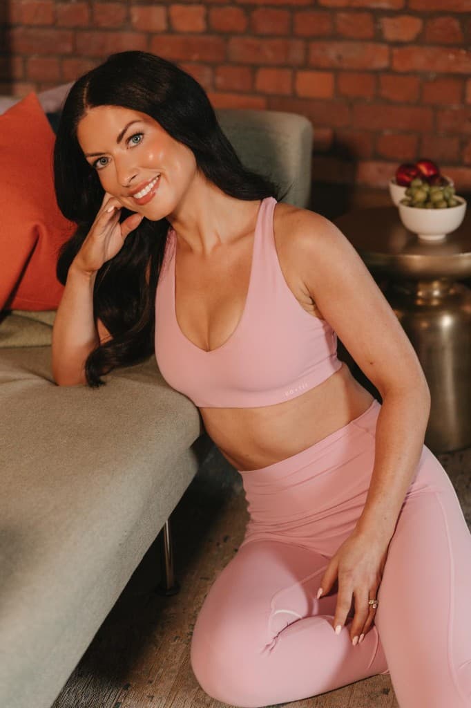 Woman in activewear smiling in a cosy living space